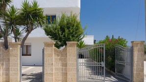A gated entrance with stone walls, a clear sky, and a building with a white facade and a window. - Vidamarina - Camere al Mare (Torre Castiglione)