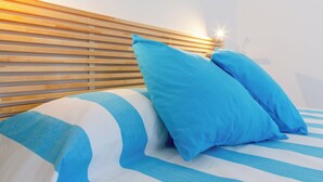 A bed with blue and white striped bedding, two blue pillows, and a wooden headboard. - Vidamarina - Camere al Mare (Torre Castiglione)