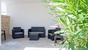 A patio area with three dark wicker chairs and a sofa, a small table, and a potted plant. - Vidamarina - Camere al Mare (Torre Castiglione)