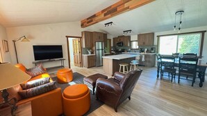 A modern living room with a sofa, ottomans, and a TV. - Ranch Retreat in Wine Country - Horses & Views! (Santa Ynez)