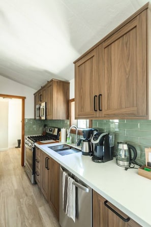 A modern kitchen with wooden cabinets, stainless steel appliances, and a tiled backsplash.