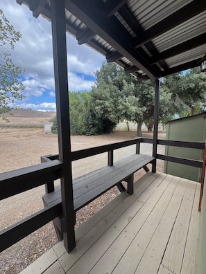 A covered outdoor area with a wooden bench and a metal railing.