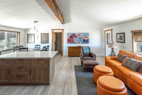 A spacious living area with a large island, a leather sofa, and a painting on the wall.