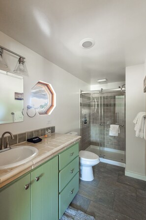 A bathroom with a double sink, a toilet, a shower with glass doors, and a skylight. - Wine Country Ranch Retreat on a Working Horse Ranch (Santa Ynez)