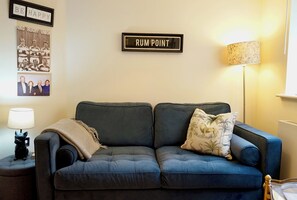 Un salon avec un canapé bleu foncé, une lampe et un panneau encadré sur lequel on peut lire : « RUM POINT ».