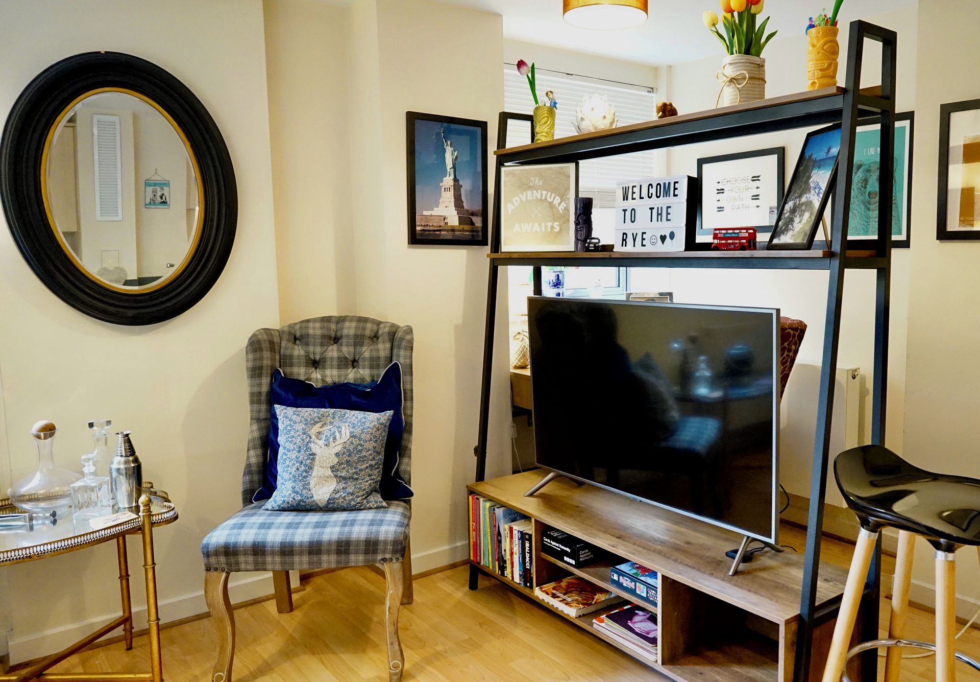 A living room with a television, a chair, a bookshelf, and a mirror.