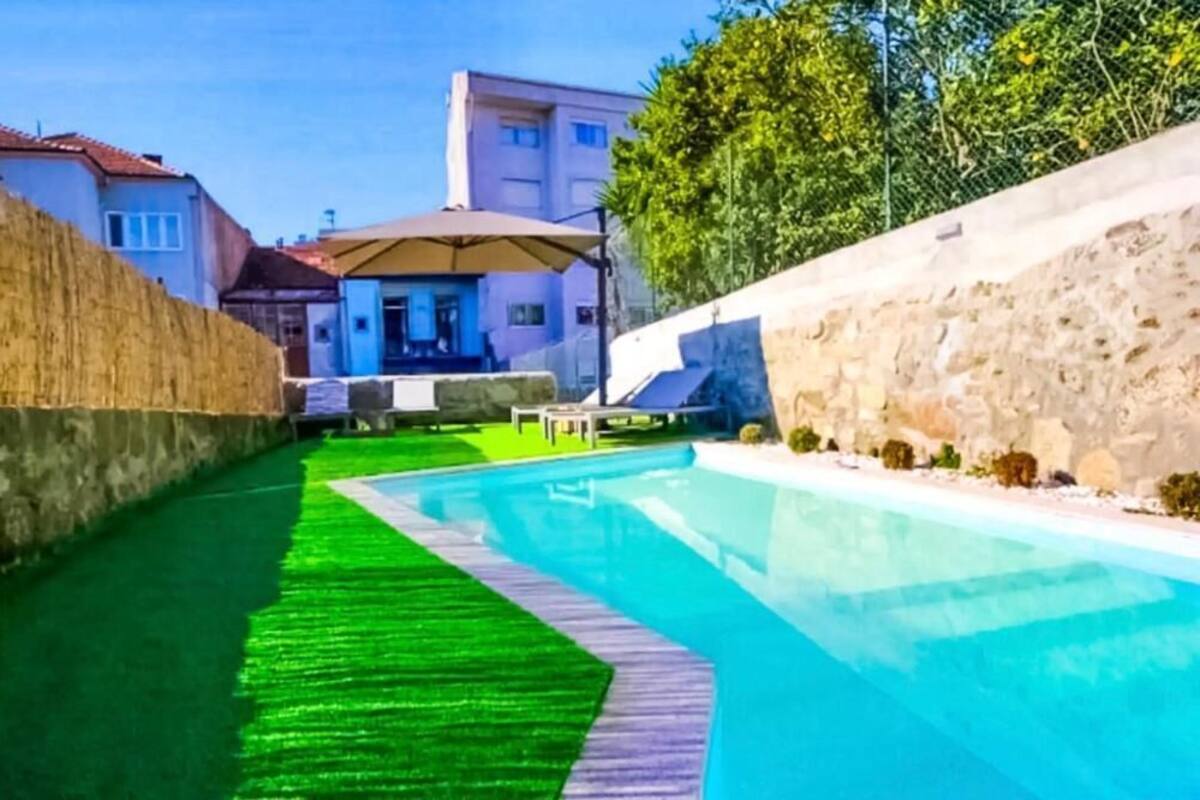 A swimming pool with a stone wall on one side and a building in the background.