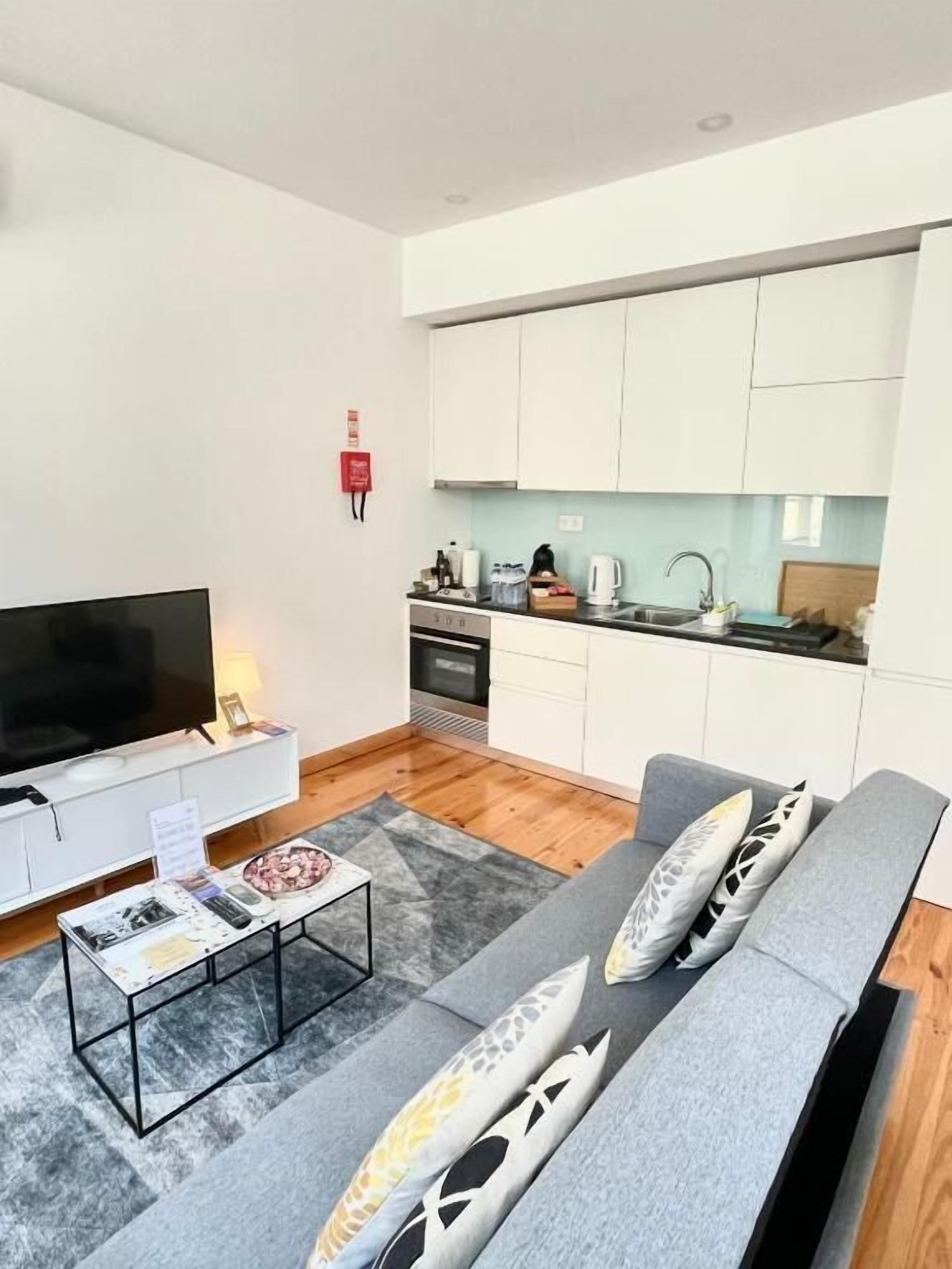 Un moderno salón con un sofá gris, una mesa de centro y un televisor de pantalla plana.
