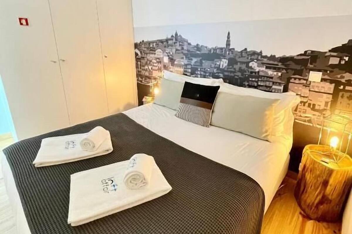 A hotel room with a bed, a laptop, and a cityscape view.