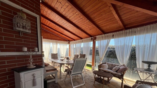 Un patio couvert doté d’un sol en pierre, d’un plafond en bois et de mobilier blanc.
