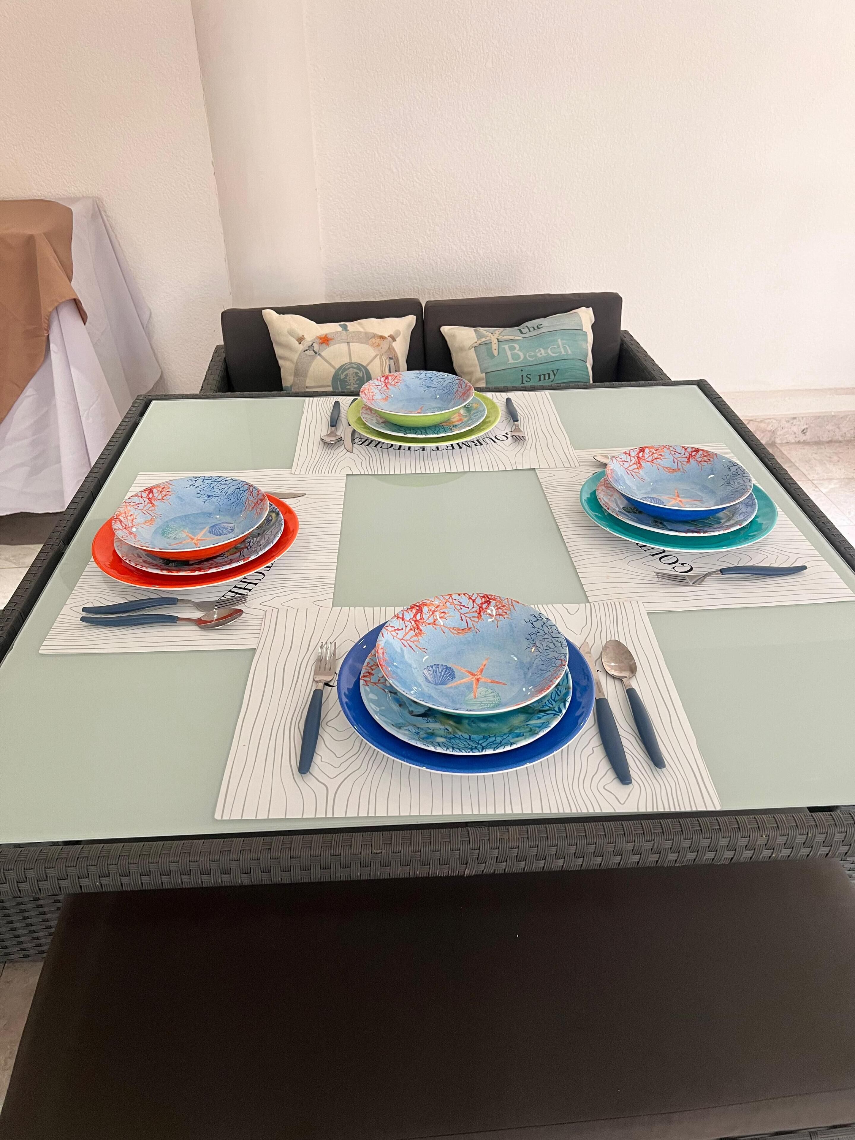 Un tavolo da pranzo con piatti e posate, su un runner decorativo.