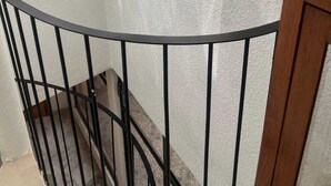 Eine Treppe mit Metallgeländer und einer strukturierten Wand.