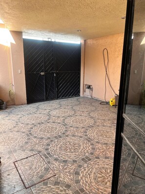 A tiled floor with a geometric pattern, a black gate, and a yellow device on the wall. - Charming Spacious Home in a Peaceful & Secure Gated Community, Mexico City (Ciudad de México)