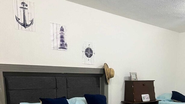Ein Hotelzimmer mit Bett, Nachttisch, Kommode und Wanduhr.