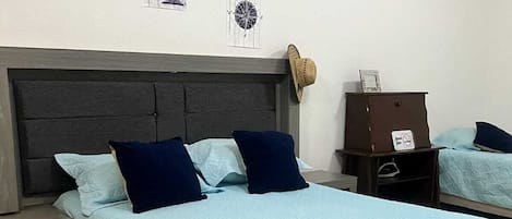 Una habitación de hotel con cama, mesita de noche, cómoda y un reloj de pared.