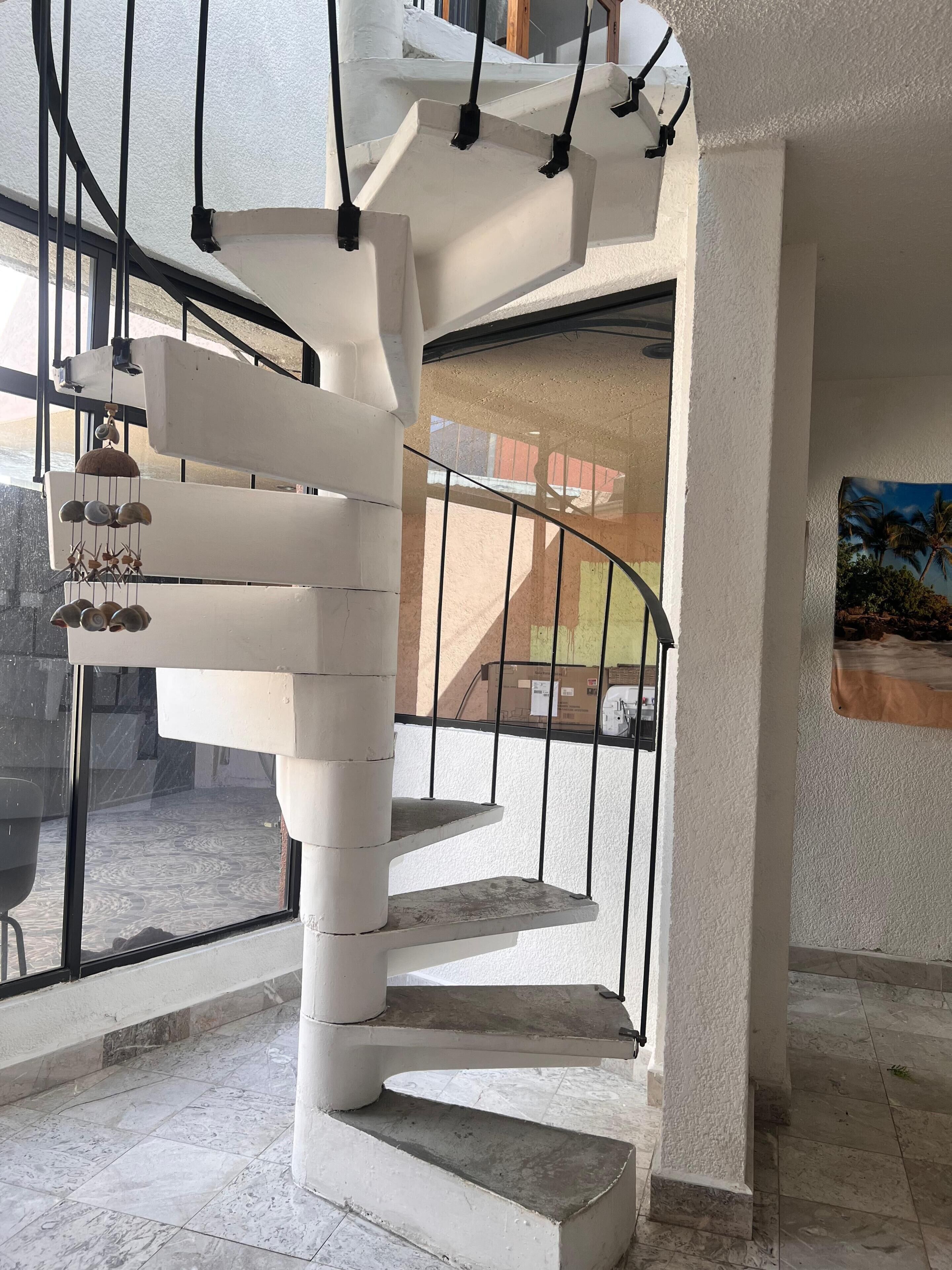 A spiral staircase with a metal railing, leading to an upper floor.