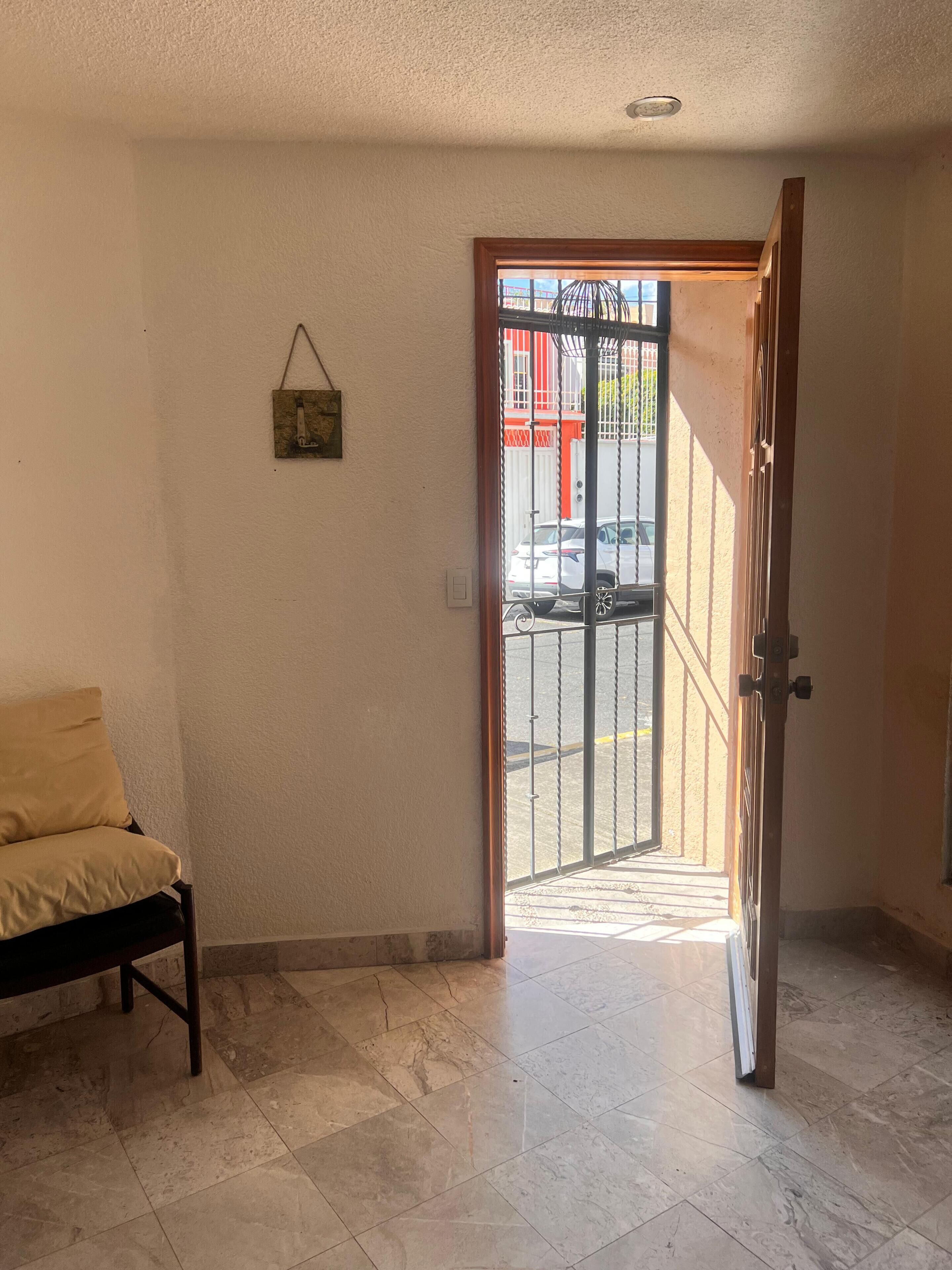 A room with a bench, a door leading outside, and a wall-mounted picture.