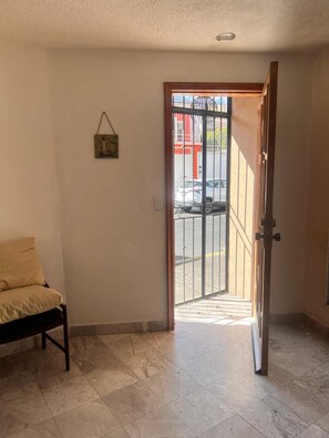 Une pièce avec un banc, une porte donnant sur l’extérieur et un tableau accroché au mur.