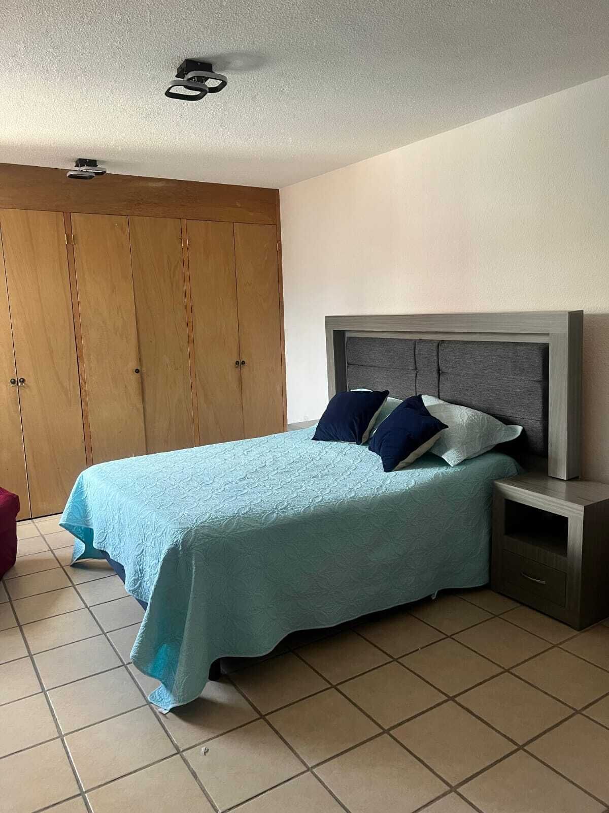 Una camera da letto con un letto, un comodino, un armadio e una ventola a soffitto.