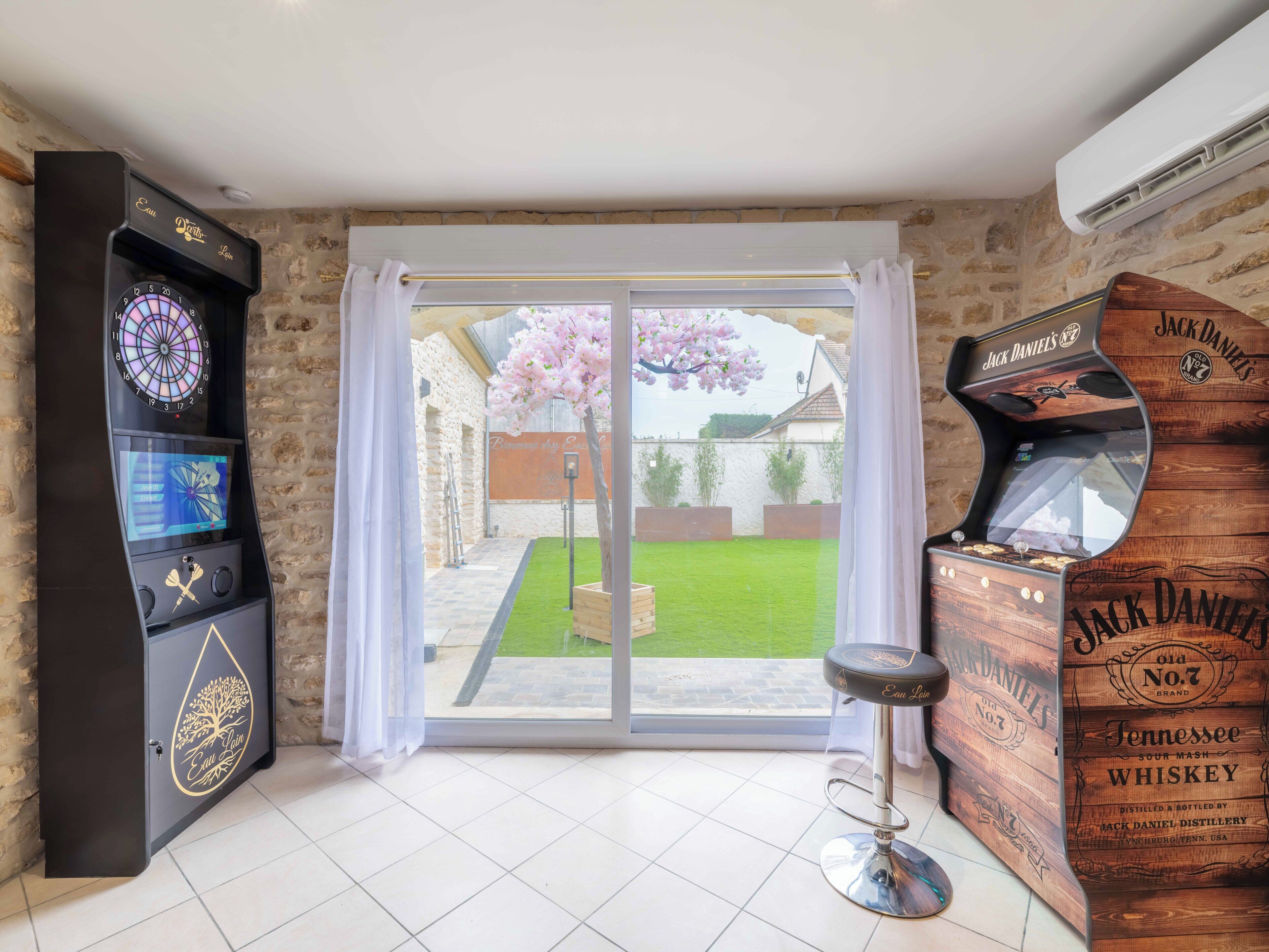 A room with a dartboard, a bar stool, and a wooden cabinet labeled "Jack Daniel's".