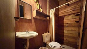 Une salle de bain en bois avec un lavabo, des toilettes et un rideau de douche.