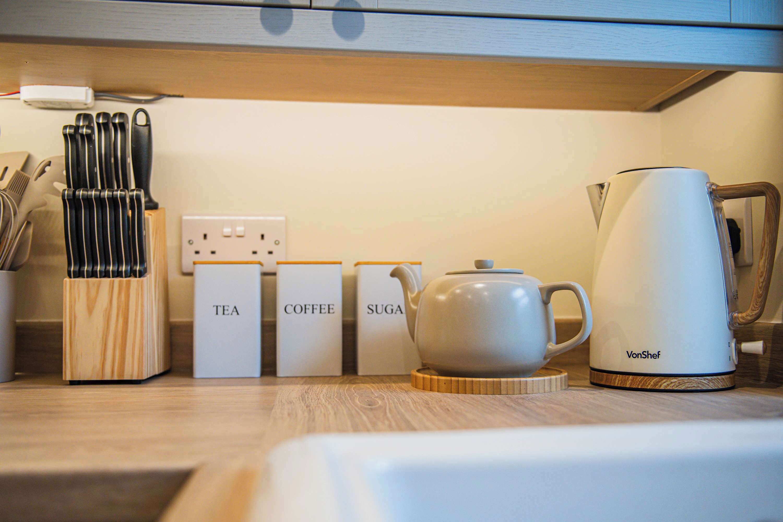 A kitchen counter with a tea set, coffee set, and sugar container.