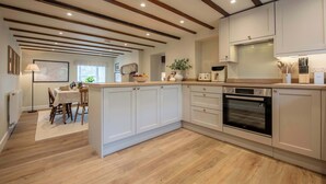 A modern kitchen with wooden beams, white cabinetry, and a central island.