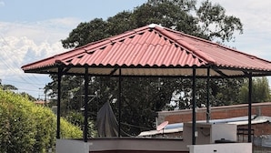Un espace extérieur abrité, doté d’un toit rouge, d’un banc et d’une antenne parabolique.