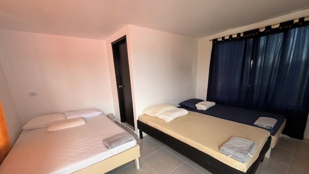 Une chambre avec deux lits, une porte et une fenêtre avec des rideaux.