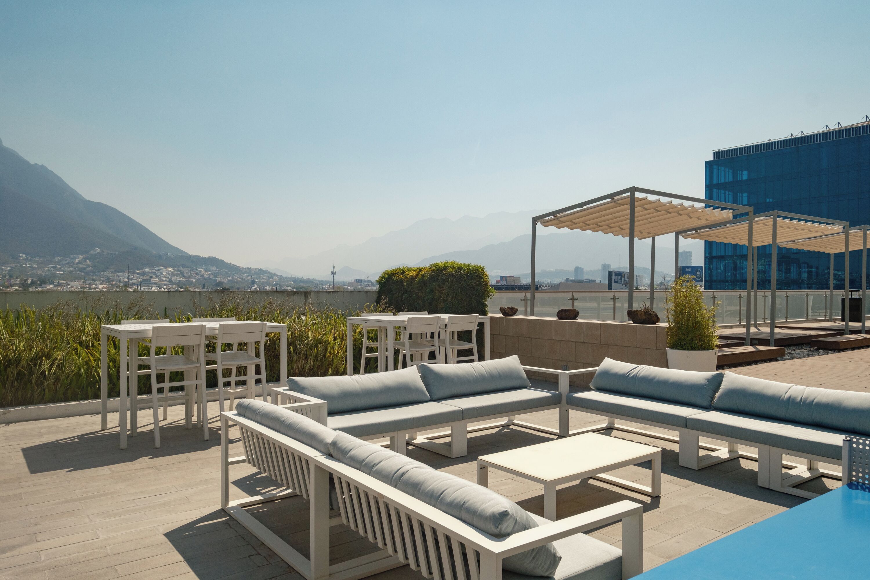 Terraço no telhado com área de estar ao ar livre, piscina e vista para montanhas e paisagem urbana.