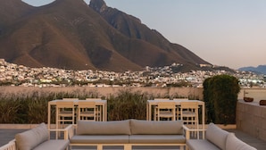 En takterrass med en soffa, stolar och ett bord, med utsikt över en stad och berg.