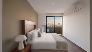 Ett modernt hotellrum med en stor säng, en sänglampa, en TV och utsikt över staden genom ett stort fönster.