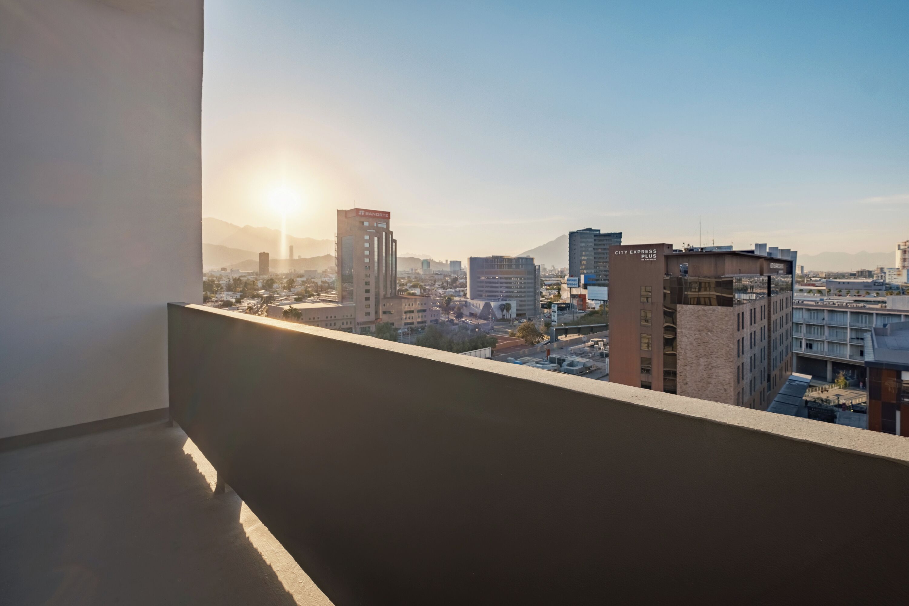 Vista panorámica de la ciudad desde un balcón, con edificios y cielo despejado.