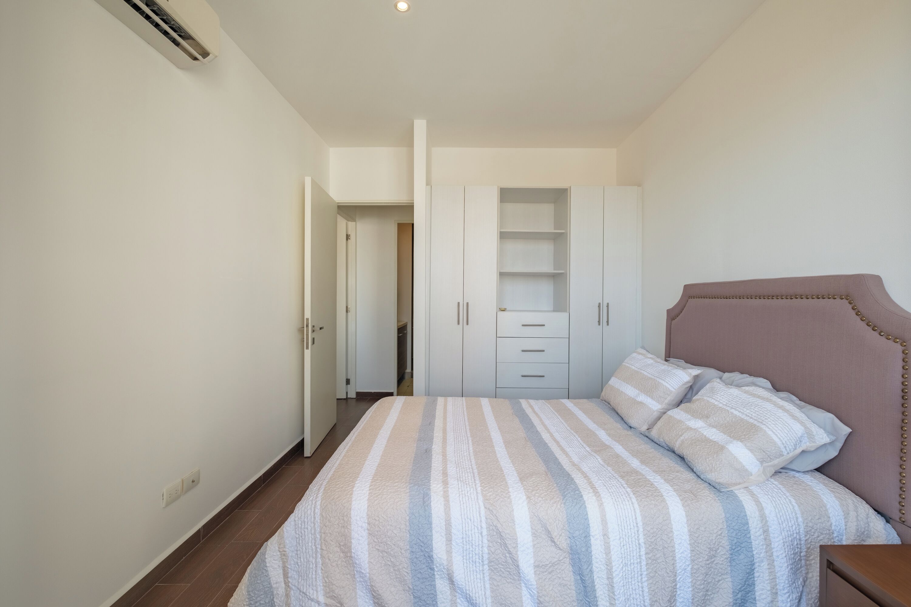 A bedroom with a bed, a wardrobe, and a nightstand.