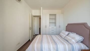 A bedroom with a bed, a wardrobe, and a nightstand.