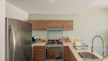 Una cocina moderna con electrodomésticos de acero inoxidable, armarios de madera y un horno empotrado.