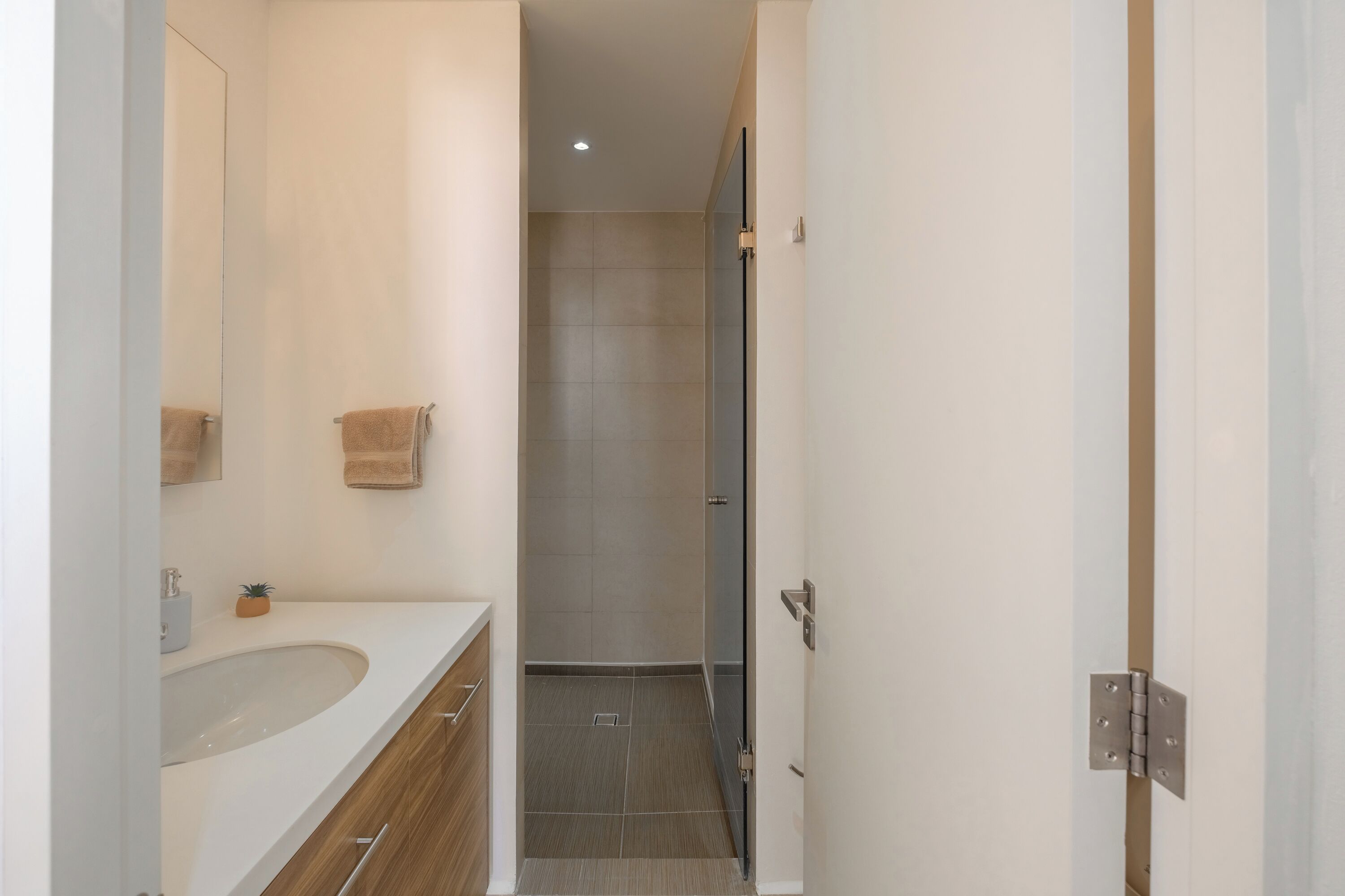 A modern bathroom with a sink, mirror, and towel rack.