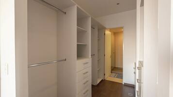 A hallway with a closet, a door leading to another room, and a wooden floor.