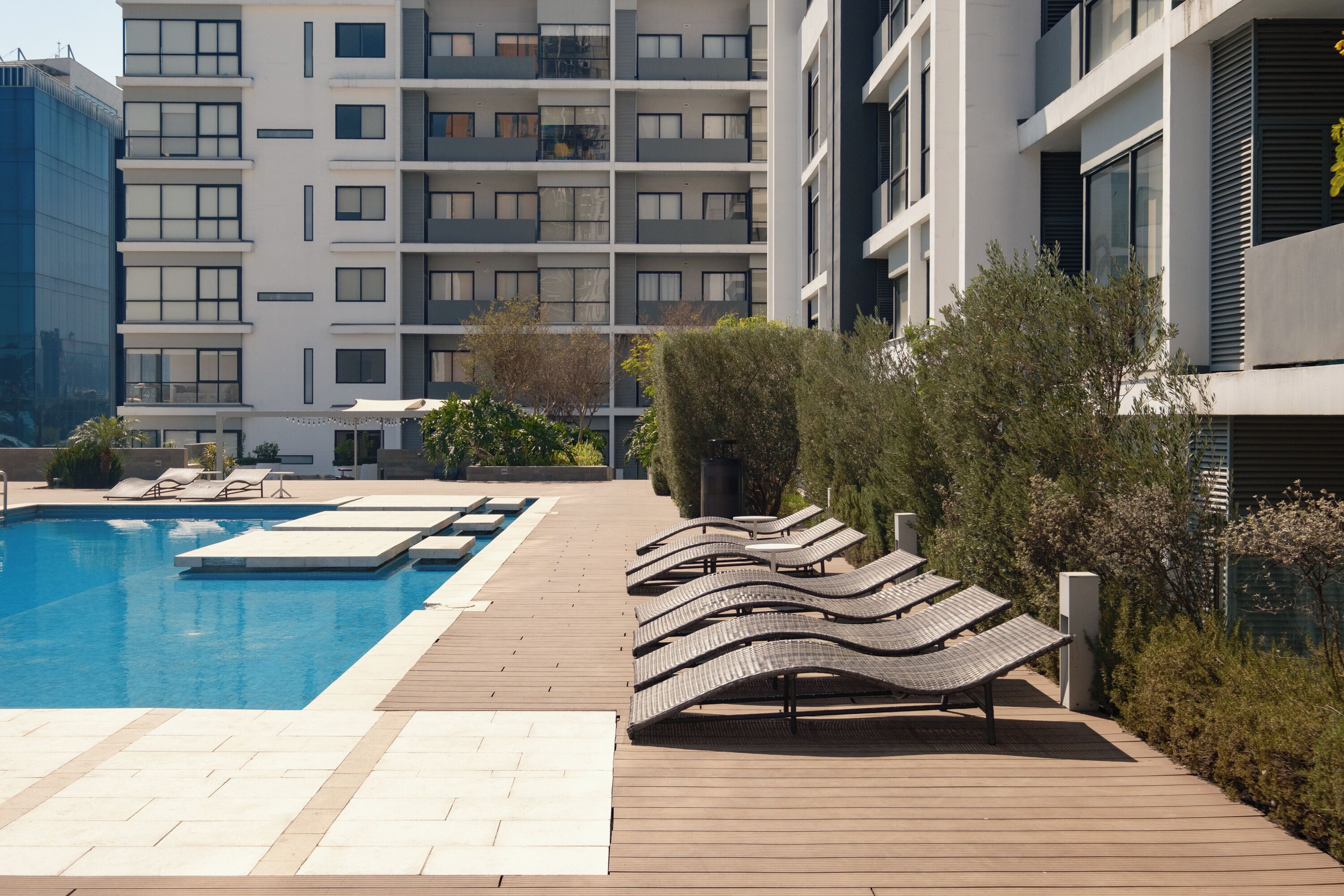 Un bâtiment moderne doté d’une piscine, de chaises longues et d’une terrasse en bois.