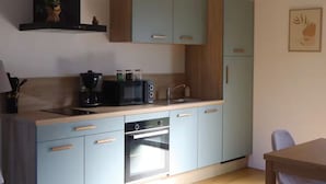 Una cocina compacta con armarios azul claro, horno empotrado, microondas y cafetera.