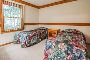 A bedroom with two beds, a wooden nightstand, and a window with vertical blinds. - 2BR Retreat nr Downtown Helen | Pool & Gym Access! (Helen)