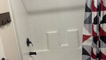 A bathroom with a white bathtub, a toilet, and a shower curtain with a geometric pattern.