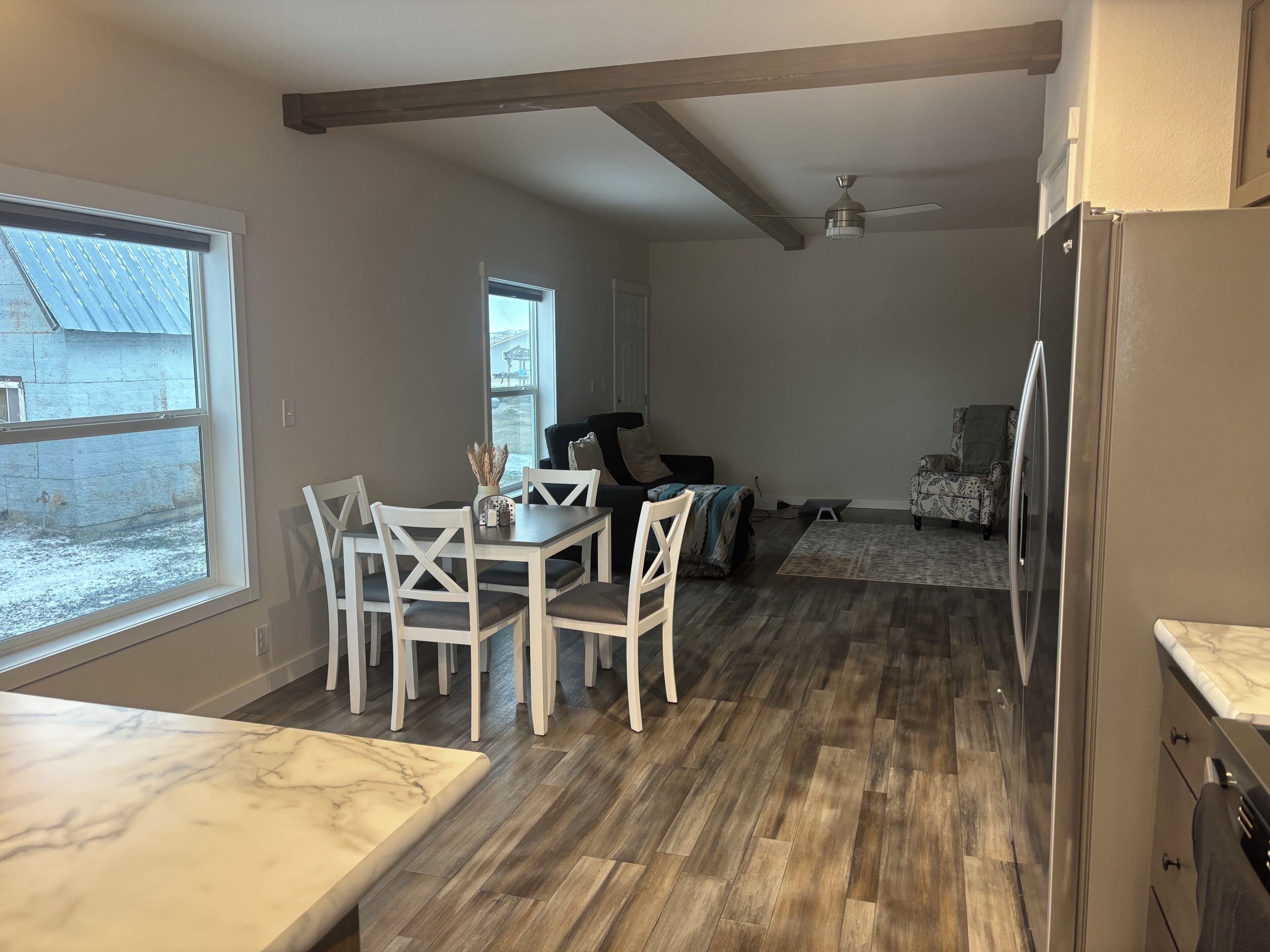 A dining area with a marble countertop, white chairs, and a view of a snowy landscape through large windows.