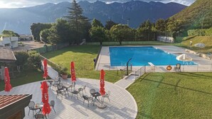 Una piscina con montagne sullo sfondo, area relax all'aperto e recinzione.