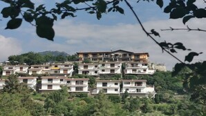 Un quartiere residenziale su una collina, con edifici a più piani, alcuni con balconi, immerso nel verde.