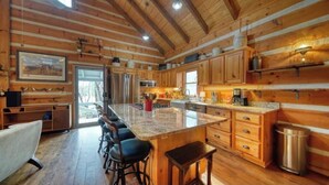 A spacious kitchen with wooden cabinets, a large island with bar stools, and a view of the outdoors. - Near Toccoa River • Hot Tub • Fire Pit • Gameroom - Holiday Home (Blue Ridge)