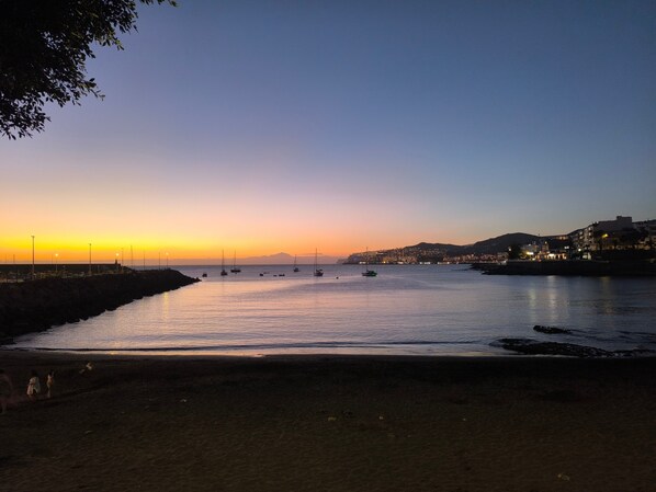 A coastal scene with a calm sea, boats, and a cityscape in the background. - Sunset Star Holiday Home: Sea Views from Rooftop Solarium, Shared Terrace & Wi-Fi (Arguineguín)