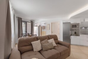 A modern living room with a sofa, a dining area, and a kitchen with appliances. - Sunset Star Holiday Home: Sea Views from Rooftop Solarium, Shared Terrace & Wi-Fi (Arguineguín)