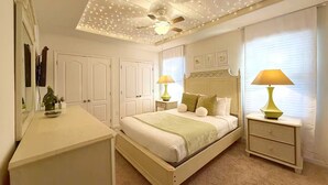 Ein Schlafzimmer mit einem Bett, zwei Nachttischen, einem Deckenventilator und Lichterketten.