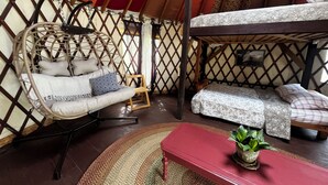 A cozy interior with a hanging chair, a bench, and a bed. - Relax in a Cozy, Skylit Yurt at a Farm Animal Sanctuary (Pittsboro)
